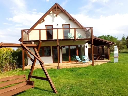 a house with a glass roof and a swing at Dom z pięknymi widokami na jezioro ryńskie ilasy. in Rybical