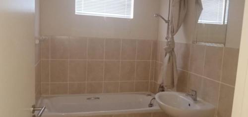 a bathroom with a bath tub and a sink at Bougain Villas in Cape Town