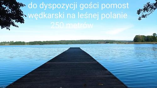 a dock in the middle of a lake at Dom z pięknymi widokami na jezioro ryńskie ilasy. in Rybical