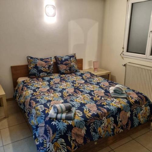um quarto com uma cama com um cobertor colorido e almofadas em Grand appartement confortable em Andolsheim
