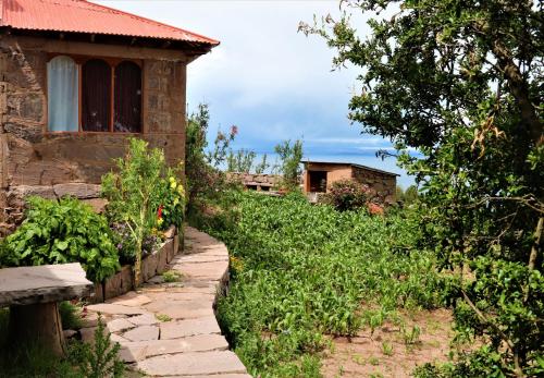 WHITE SAND Taquile Lodge في Huillanopampa: منزل به مسار حجري بجوار مبنى