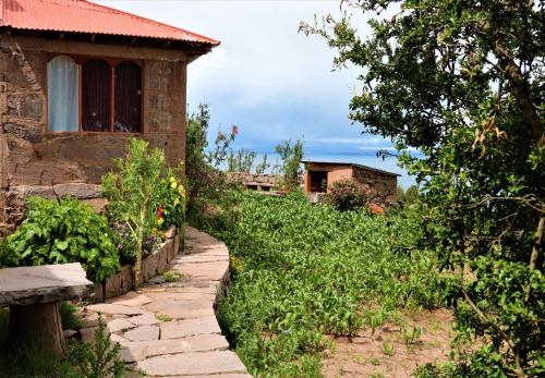 una casa con un camino de piedra junto a un edificio en WHITE SAND Taquile Lodge, en Huillanopampa