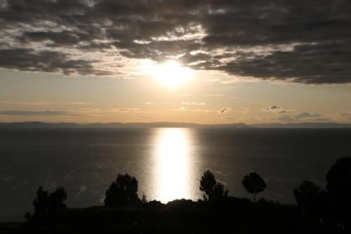 una puesta de sol sobre el agua con el sol en el cielo en WHITE SAND Taquile Lodge, en Huillanopampa