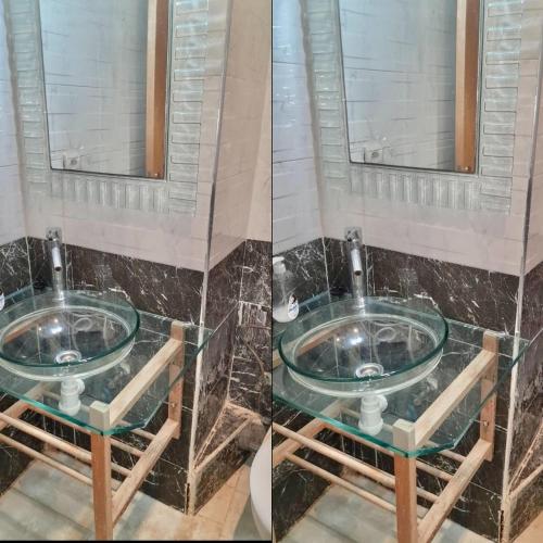 ein Badezimmer mit einem Glaswaschbecken und einem Spiegel in der Unterkunft Marina Golf appartement de luxe in Asilah