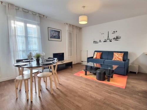 un salon avec une table et un canapé bleu dans l'établissement Le cocon d'Ariane *Disney*Paris*Gare à 100m*, à Chessy
