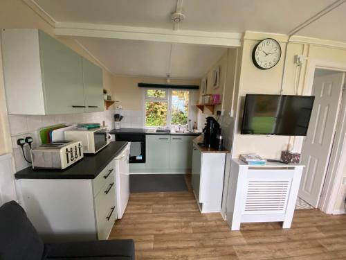 a kitchen with white cabinets and a clock on the wall at Bay view chalet, 28 Sea Valley in Bucks Mills