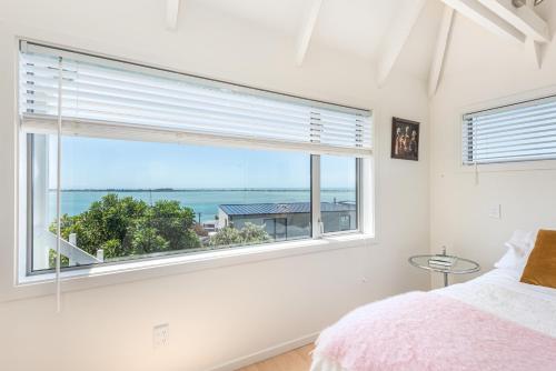 a bedroom with a window with a view of the ocean at Christchurch - Art space, sea views, private in Christchurch