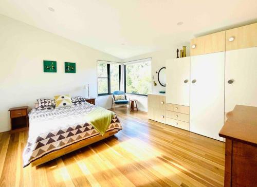 a bedroom with a bed and a wooden floor at PencilWood Farm - Berry rainforest sanctuary in Woodhill