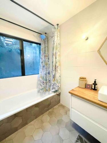a bathroom with a window and a tub and a sink at PencilWood Farm - Berry rainforest sanctuary in Woodhill