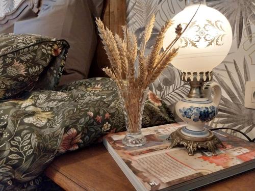 a table with a vase and a lamp on a table with a couch at La grange aux dîmes in Walcourt