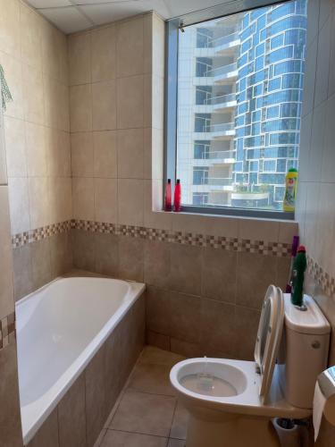 a bathroom with a bath tub and a toilet at Bellehomez in Dubai