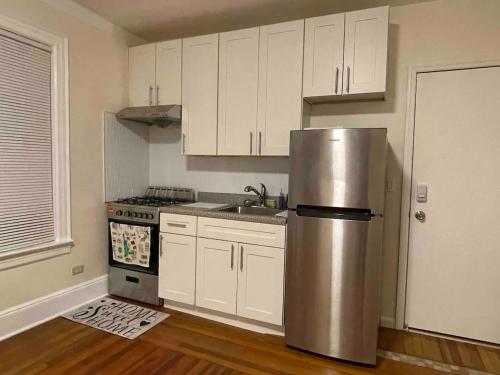 a kitchen with white cabinets and a stainless steel refrigerator at Entire Beautiful 2BR Apartment [L]. Convenient location in the heart of Queens! in Whitestone