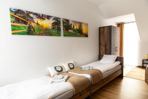 a bedroom with two beds and a painting on the wall at Apartamenty u Jakubika in Krynica Zdrój