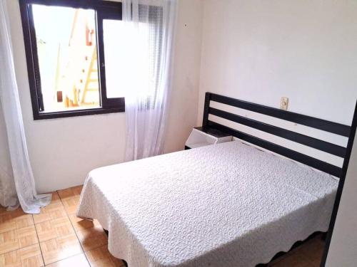 a bedroom with a white bed and a window at Casa Amarela a Beira Mar entre Arroio do Sal e Torres in Arroio do Sal