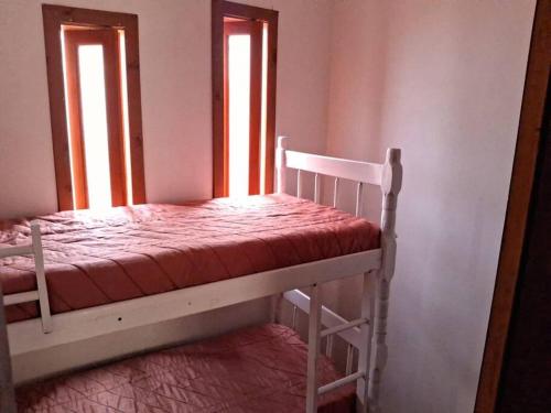 a bunk bed in a room with two windows at Casa Amarela a Beira Mar entre Arroio do Sal e Torres in Arroio do Sal