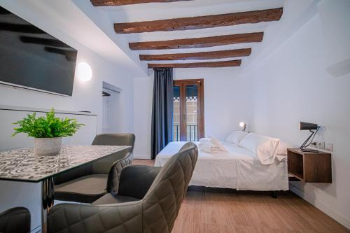 Habitación con cama, mesa y sillas. en ESTUDIO ROMAN & CATHEDRAL EXPERIENCe, en Tarragona