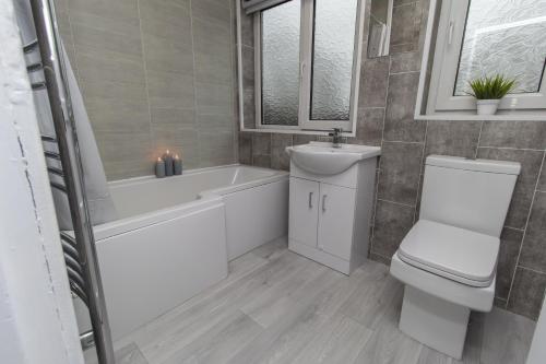 a bathroom with a toilet and a tub and a sink at Dwellcome Home Ltd 3 Bedroom Boldon House - see our site for assurance in Boldon