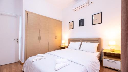 um quarto com uma cama grande e lençóis brancos em Aelia Apartment em Artemida