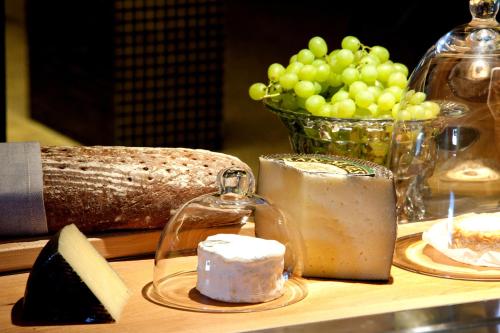 a table topped with cheese and a bowl of green grapes at Nala Individuellhotel in Innsbruck