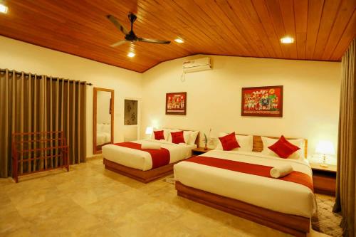 a bedroom with two beds and a ceiling at Thisath Villa in Gonapinuwala West