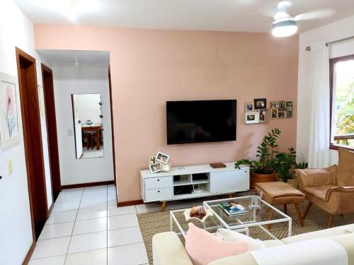 uma sala de estar com um sofá e uma TV em Flat Sol do Ipanema em Itacaré