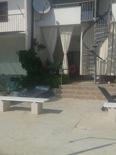 a white bench in front of a building with stairs at Apartments Toma Bajnice Directly in Krilo