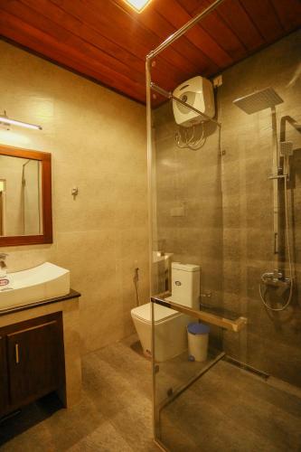 a bathroom with a shower and a toilet and a sink at Thisath Villa in Gonapinuwala West