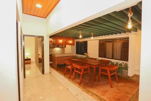 uma cozinha e sala de jantar com uma mesa de madeira e cadeiras em Thisath Villa em Gonapinuwala West