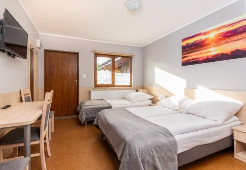 two beds in a room with a table and a desk at Rajska Mierzeja in Sarbinowo