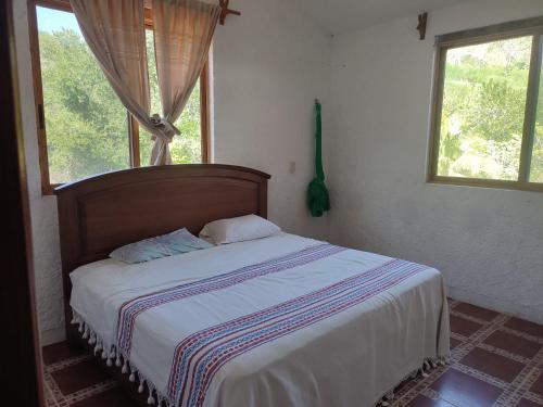 1 dormitorio con 1 cama en una habitación con 2 ventanas en Casa Galaa Guiba', en Tangolunda