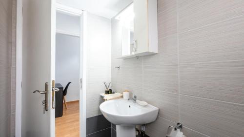 La salle de bains blanche est pourvue d'un lavabo et d'un miroir. dans l'établissement Aelia Apartment, à Artemi