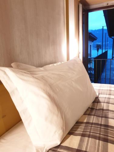a bed with white pillows in a room with a balcony at Piccolo Hotel Olina in Orta San Giulio
