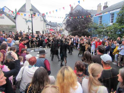 a crowd of people walking down a street with men on horses at The Old Post House in Moretonhampstead
