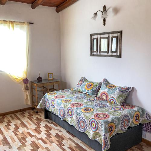 a bedroom with a bed with a colorful comforter and a window at SOL Y SIERRAS in Mina Clavero