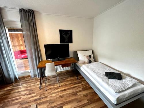 a room with a bed and a desk with a television at OhPardon! GAILDORF - Monteurwohnung im EG, Einzelbetten, Loggia & Garten in Gaildorf