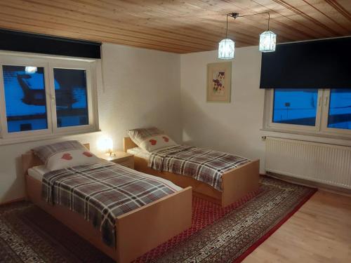 a bedroom with two beds and two windows at Allgäu Bergblick in Leutkirch im Allgäu