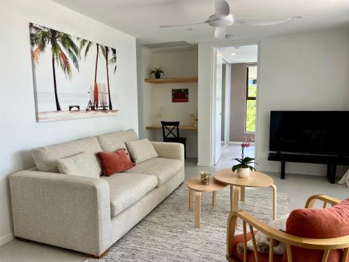 a living room with a couch and a tv at NEW - Sunny Coolum Beach Retreat in Coolum Beach