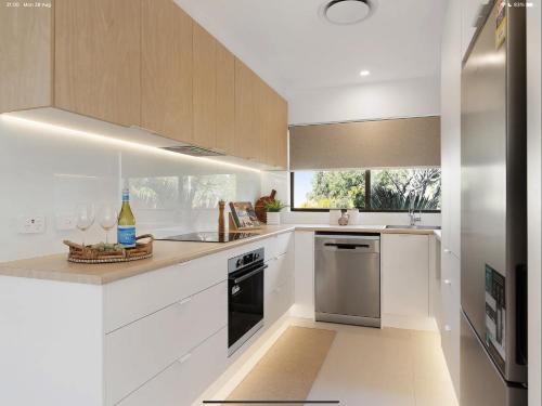 a white kitchen with a sink and a dishwasher at NEW - Sunny Coolum Beach Retreat in Coolum Beach