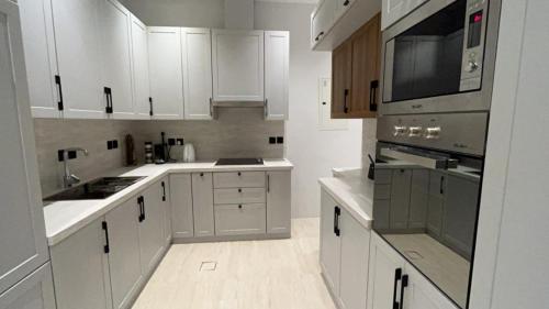a kitchen with white cabinets and a stove top oven at Safa Complex Apartment in Riyadh