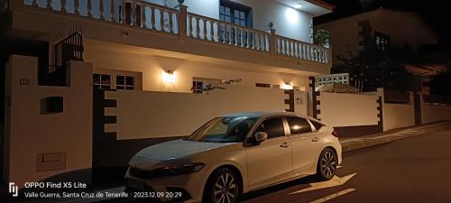 une voiture blanche garée devant une maison la nuit dans l'établissement Cotufa Garden, à La Laguna