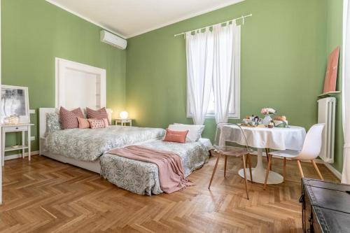 a green bedroom with a bed and a table at Studio liberty a 100 metri dalle mura in Bassano del Grappa