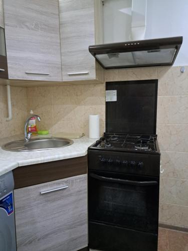a kitchen with a black stove and a sink at Сдаётся почасово, посуточно квартира in Edineţ