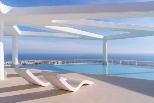 a view of a swimming pool with white chairs at Gran Canet 2BR! Walk to Beach, Sea View, Sauna & Gym in Canet de Berenguer