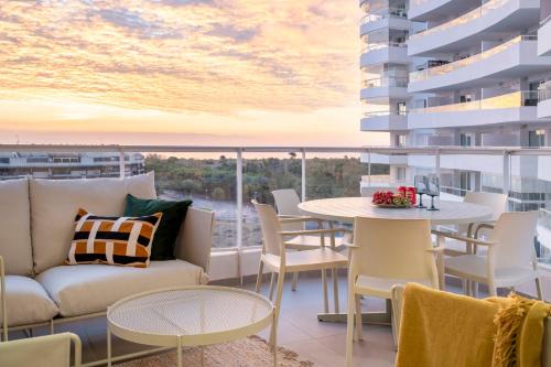 a living room with a couch and a table on a balcony at Gran Canet 2BR! Walk to Beach, Sea View, Sauna & Gym in Canet de Berenguer