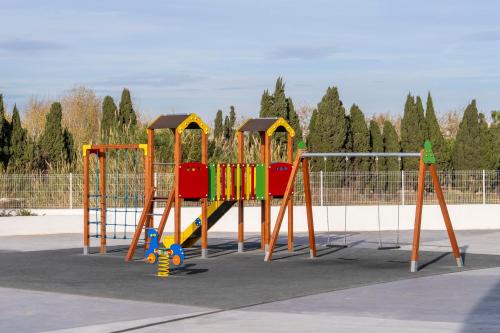 a playground with a colorful swing set in a park at Gran Canet 2BR! Walk to Beach, Sea View, Sauna & Gym in Canet de Berenguer