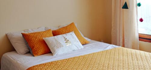 a bed with orange and white pillows on it at LA CASA DE PASCUALA in Villa Rica