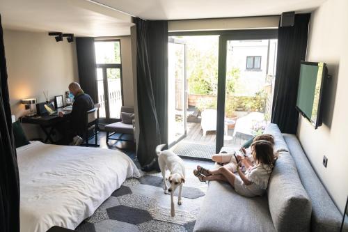 two girls sitting on a couch in a bedroom with a dog at Museum Suites in Antwerp