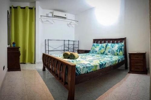 1 dormitorio con cama de madera y cortina verde en Casa San Sebastian, en Santa Marta