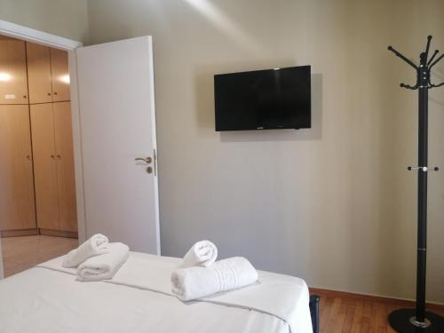 a bedroom with two white beds with a tv on the wall at Central Home in Kalamata