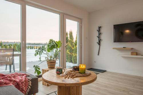 salon ze stołem i dużym oknem w obiekcie Baltic Time - Domki & Spa w Ostrowie